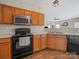 Kitchen featuring stainless steel appliances, oak cabinets, and durable laminate flooring at 3301 Old Knobbley Oak Dr, Gastonia, NC 28056