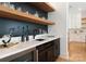 A stylish bar featuring wood floating shelves, dark cabinets, and light countertops at 3308 Carmel Rd, Charlotte, NC 28226
