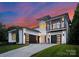 Elegant, modern home with black framed windows, a balcony and black garage doors against a vibrant sunset sky at 3308 Carmel Rd, Charlotte, NC 28226