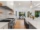 Modern kitchen with stainless appliances, an island with white countertops, and open shelving overlooking a dining area at 3308 Carmel Rd, Charlotte, NC 28226