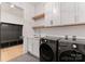 Modern laundry room featuring gray tile floors, gray washer/dryer, sink and storage at 3308 Carmel Rd, Charlotte, NC 28226