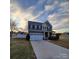 Charming two-story home featuring a two-car garage, neutral paint, and a well-manicured lawn during a colorful sunset at 3717 English Garden Dr, Gastonia, NC 28056