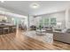 Open-concept living room featuring wood floors, large windows, and neutral décor seamlessly connecting to the dining area and kitchen at 4014 Stockbrook Dr, Charlotte, NC 28215