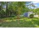 Lush backyard featuring green grass, mature trees, and an outbuilding with blue painted deck at 4911 Rivergreen Ln, Charlotte, NC 28227
