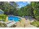 Backyard swimming pool surrounded by lounge chairs, dining table, and lush greenery at 4911 Rivergreen Ln, Charlotte, NC 28227