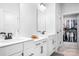 Bright bathroom featuring double sinks, white cabinets, and a walk-in closet with organized storage at 6365 Ashton Park Dr, Denver, NC 28037