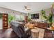 Cozy living room featuring a comfortable leather sofa, natural lighting, and decorative plant accents at 6412 Bluegill Rd, Charlotte, NC 28216