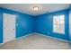 This bedroom features a bright blue paint with a single window and a white door at 6414 Goldenblush Cir, Charlotte, NC 28269