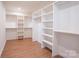 Walk-in closet featuring hardwood floors and white shelving units at 6711 Creft Cir, Lake Park, NC 28079
