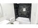This bathroom features a tub and shower with black marble tile, a toilet, and a white vanity at 703 Central Nw Dr, Concord, NC 28027