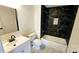 This bathroom features a tub and shower with black marble tile, a white vanity, and a black faucet at 703 Central Nw Dr, Concord, NC 28027