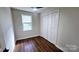 This bedroom features hardwood floors, a window with blinds, a ceiling fan, and a closet with white panel doors at 703 Central Nw Dr, Concord, NC 28027