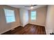 This cozy bedroom features hardwood floors, two windows with blinds, a ceiling fan, and a closet with white panel doors at 703 Central Nw Dr, Concord, NC 28027