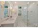 Bright bathroom with double vanity, white cabinets, marble countertop and glass-enclosed walk in shower at 726 E Kingston Ave, Charlotte, NC 28203
