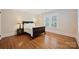 Bedroom featuring hardwood floors, neutral walls, plantation shutters, and dark wood furniture at 726 E Kingston Ave, Charlotte, NC 28203