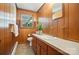 Bathroom with wood paneling, toilet, vanity with storage, and a window with shutters at 900 Nance St, Kannapolis, NC 28083