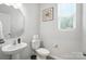 Clean and simple powder room with pedestal sink, toilet, and window for natural light at 11246 Bartrams Way, Charlotte, NC 28278