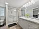Bright bathroom featuring a double sink vanity with granite counters and a glass enclosed shower at 1140 Randall Ct, Concord, NC 28025
