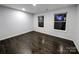 An empty bedroom with two windows and dark hardwood flooring at 11419 Leadenhall Ln, Charlotte, NC 28262