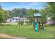 Well-maintained backyard featuring a wooden playset with a slide, a fenced perimeter, and a detached garage at 1744 Emerywood Dr, Charlotte, NC 28210