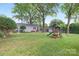 Expansive backyard with wooden playset, seating, a detached structure with an outdoor area, and shade trees at 1744 Emerywood Dr, Charlotte, NC 28210