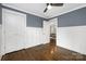 Bedroom featuring blue accent wall, wainscoting, hardwood floors, ceiling fan, and trim at 1744 Emerywood Dr, Charlotte, NC 28210