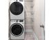 Functional laundry room featuring stacked washer and dryer unit and shelving for organized storage at 1744 Emerywood Dr, Charlotte, NC 28210