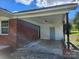 Attached carport area with brick and vinyl exterior with access door and lighting at 2448 Cambridge Dr, Lancaster, SC 29720
