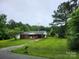 Quaint single-story brick home with covered parking, lush lawn, and mature trees at 2448 Cambridge Dr, Lancaster, SC 29720