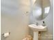 Modern powder room featuring a pedestal sink, oval mirror, and neutral paint at 349 Valley Brook Se Ln, Concord, NC 28025