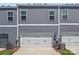 Rear view of townhome with siding, garage doors, neatly trimmed lawn, and air conditioning units at 517 Morrows Turnout Way, Pineville, NC 28134