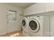 Bright laundry room featuring a modern washer and dryer, crisp white cabinets, and a door to the outside at 6117 Yellowood Rd, Charlotte, NC 28210
