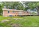 Lush backyard with a brick house, wooden deck, green grass, and mature trees offering a private outdoor oasis at 617 Oak Grove Rd, Kings Mountain, NC 28086