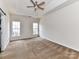 Spacious carpeted bedroom featuring a ceiling fan, tray ceiling, and many windows at 7518 Turley Ridge Ln, Charlotte, NC 28273