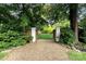 Inviting backyard entrance through white brick pillars and wooden gate surrounded by lush greenery at 802 E Franklin St, Monroe, NC 28112