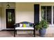 Charming front porch features a cozy bench, decorative pillow, and lovely potted flowers at 802 E Franklin St, Monroe, NC 28112