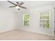 Bright bedroom with neutral carpet, ceiling fan, and natural light from two windows at 9416 Cotton Gum Rd, Charlotte, NC 28227