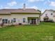 Back exterior view of the home with a manicured lawn and a covered patio with seating at 9428 Carneros Creek Rd, Charlotte, NC 28214