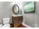 Cozy half bathroom featuring a wooden vanity, round mirror, and decorative artwork at 109 Trent Pines Dr, Mooresville, NC 28117
