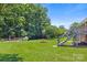 Large backyard with mature trees, a lush green lawn, and stair access to the house at 128 Howie St, Mount Holly, NC 28120