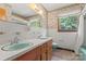 Retro bathroom featuring double sinks, wood cabinets, wallpaper, and a window view at 128 Howie St, Mount Holly, NC 28120