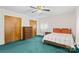 Bedroom with ceiling fan, bed with bright orange pillows, closet, and green carpet at 128 Howie St, Mount Holly, NC 28120