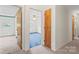 Hallway with neutral carpet, leading to bedrooms with blue carpet, and wood paneled doors at 128 Howie St, Mount Holly, NC 28120