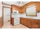 Classic kitchen with wooden cabinets, white appliances, and a window overlooking the yard at 128 Howie St, Mount Holly, NC 28120