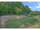 Backyard with grassy lawn, mature trees, small retaining wall, and black iron fence at 1335 Bryson Gap Dr, Fort Mill, SC 29715