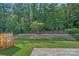Backyard with grassy lawn, mature trees, small retaining wall, and black iron fence at 1335 Bryson Gap Dr, Fort Mill, SC 29715