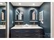 Stylish bathroom with a navy vanity with double sinks, brass fixtures, and arched mirrors against dark teal walls at 1419 Jules Ct, Charlotte, NC 28226