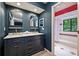 Stylish bathroom with a navy vanity with double sinks, brass fixtures, and arched mirrors and a shower-tub combination at 1419 Jules Ct, Charlotte, NC 28226
