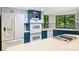 Modern kitchen features updated appliances, a gas cooktop island, blue cabinets, and large windows with wooded views at 1419 Jules Ct, Charlotte, NC 28226