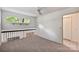 Cozy loft space featuring neutral carpet and wall paint, a ceiling fan, and staircase overlooking the room at 1419 Jules Ct, Charlotte, NC 28226